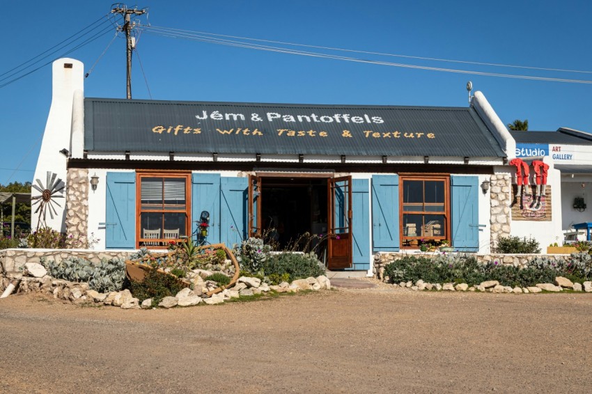 a small building with blue shutters and a black roof