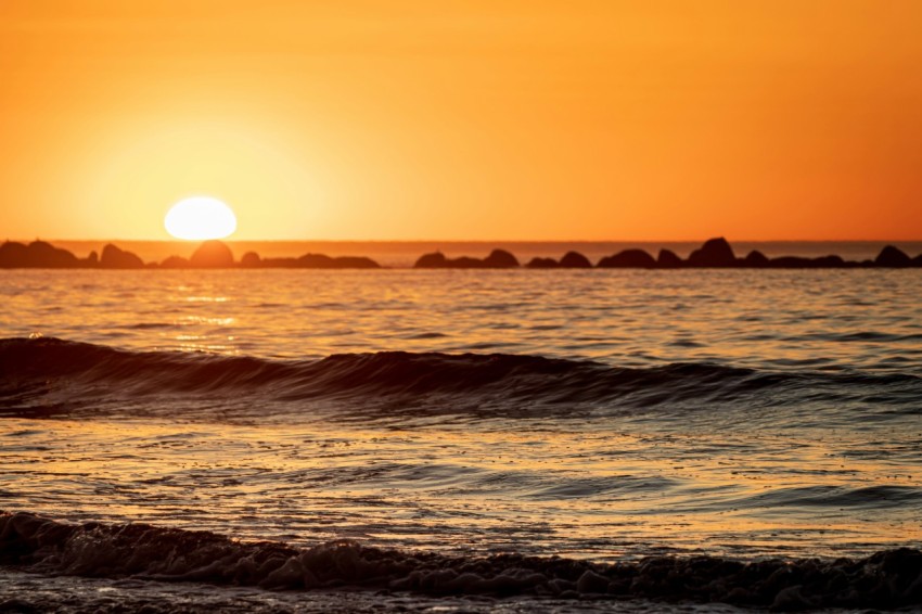 the sun is setting over the ocean with waves