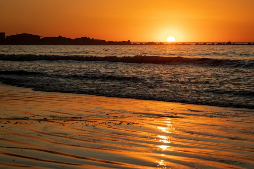 the sun is setting over the water at the beach