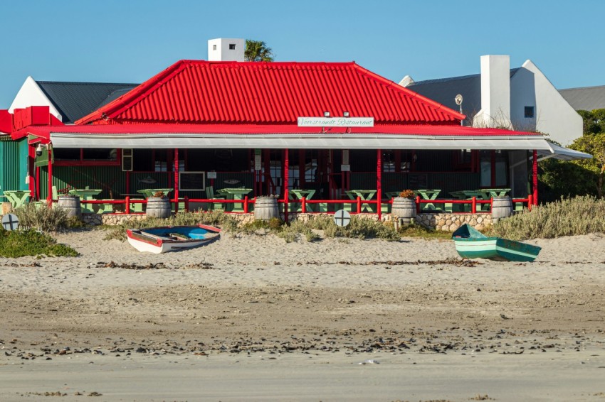 a red building with a red roof on a beach