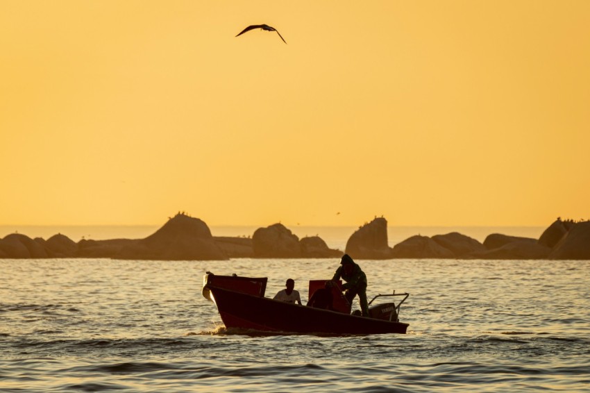 a man on a boat in the ocean at sunset M3mTO