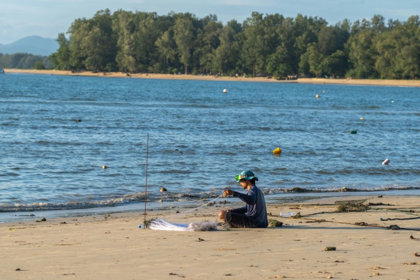 a person sitting on a beach with a surfboard