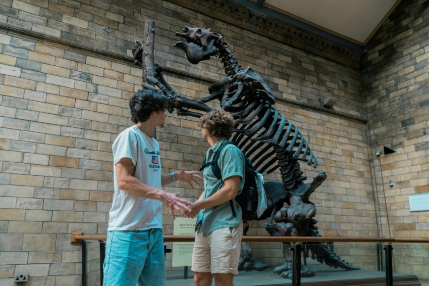 two boys standing in front of a dinosaur skeleton Td8