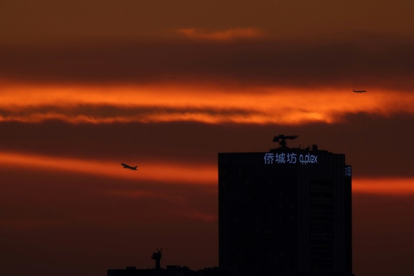 the sun is setting behind a tall building