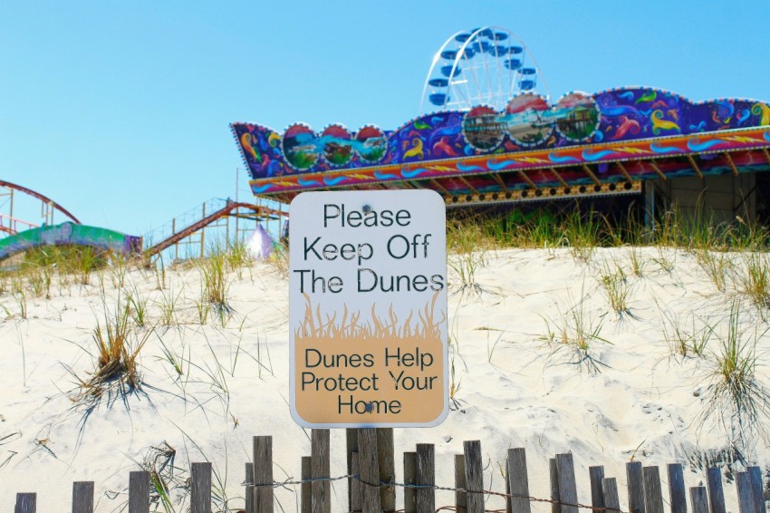 a sign on a fence that says please keep off the dunes