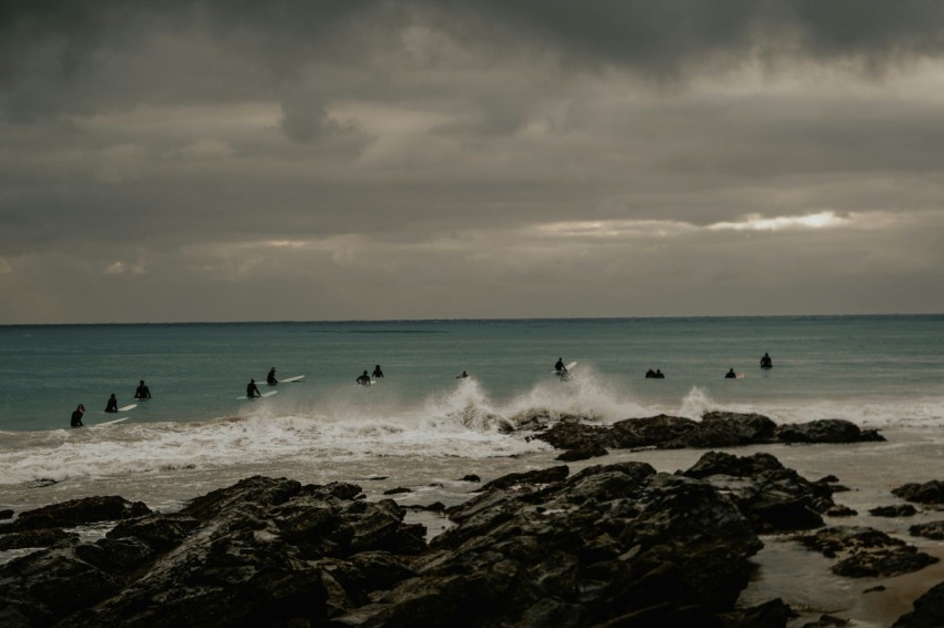 a group of people riding surfboards on top of a wave