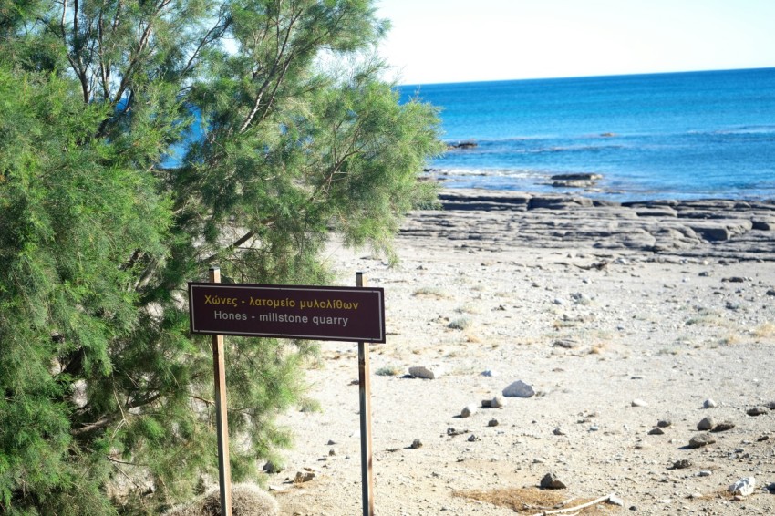 a sign on the side of a beach near the ocean