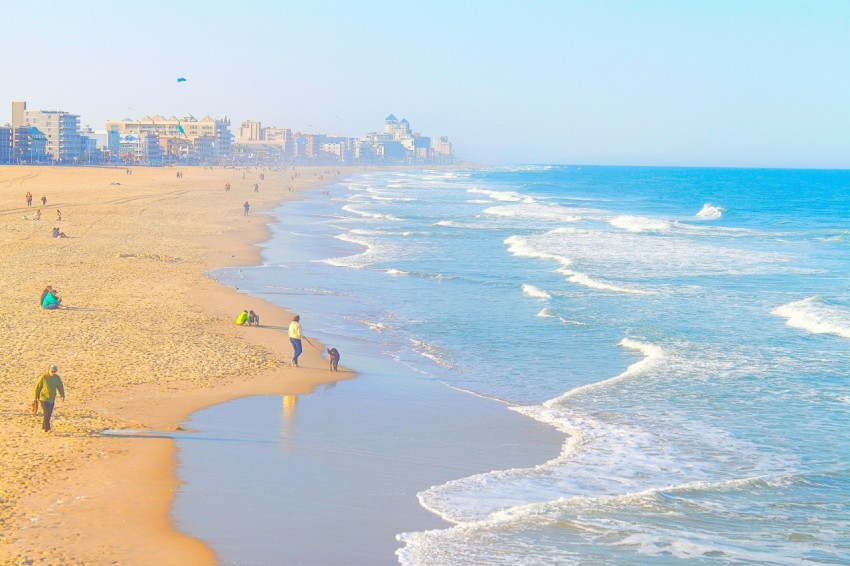 a group of people walking along a beach next to the ocean