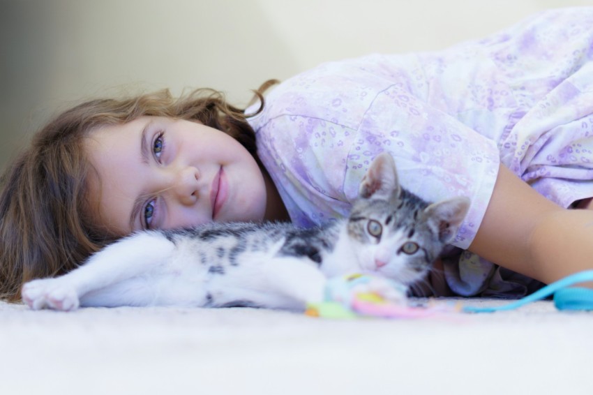 a little girl laying on the floor with a cat