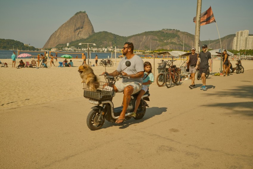 a man riding a scooter with a dog on the back of it lg