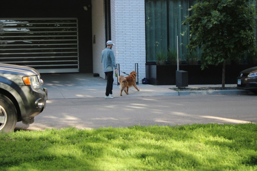 a man walking a dog in front of a garage jm5_0DPSZ