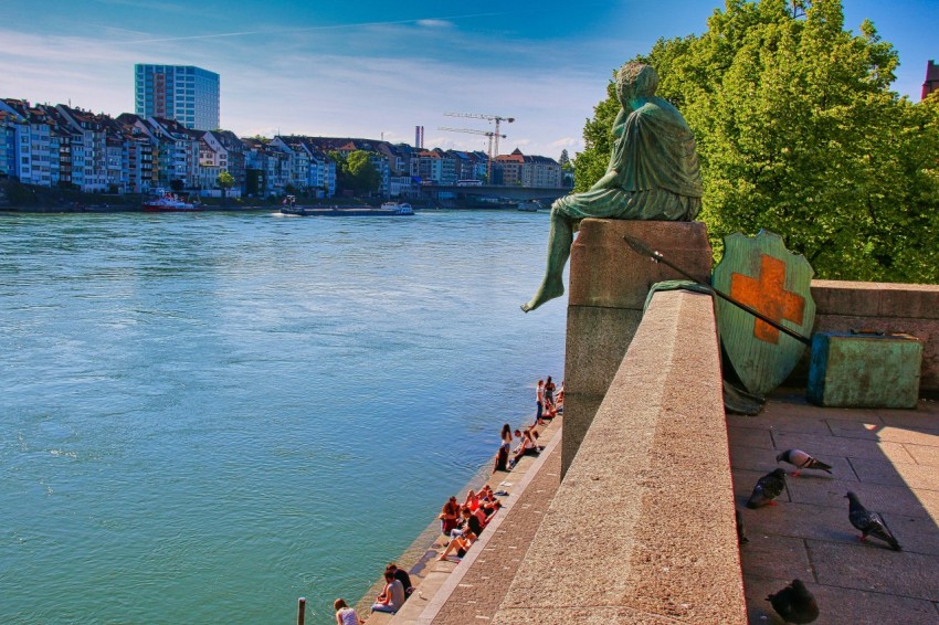 a statue of a man sitting on a ledge next to a body of water