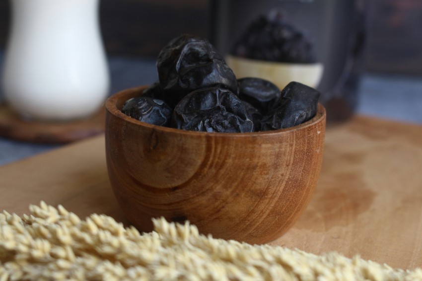 a wooden bowl filled with raisins next to a bottle of milk