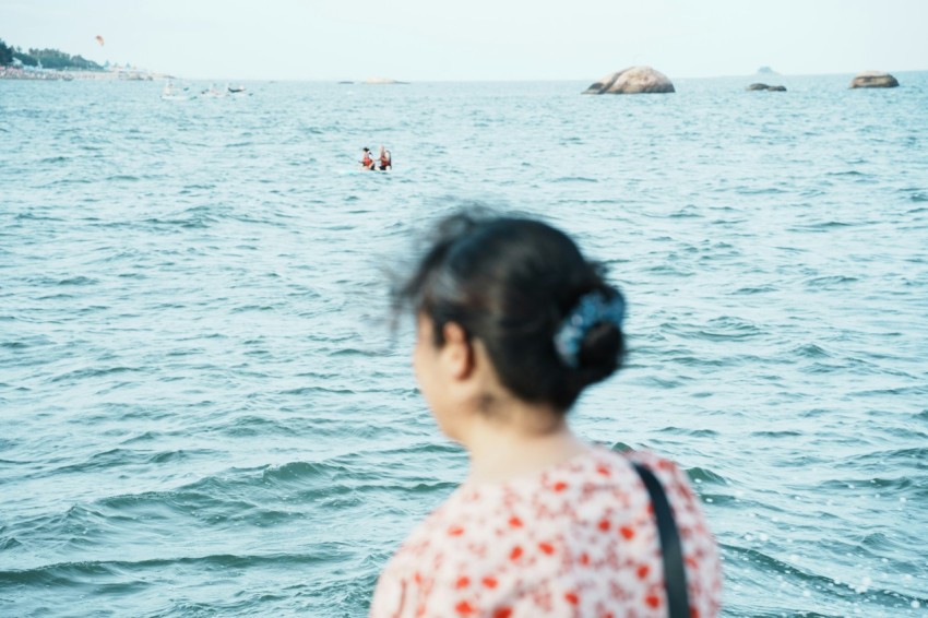 a woman standing on a boat looking at a body of water