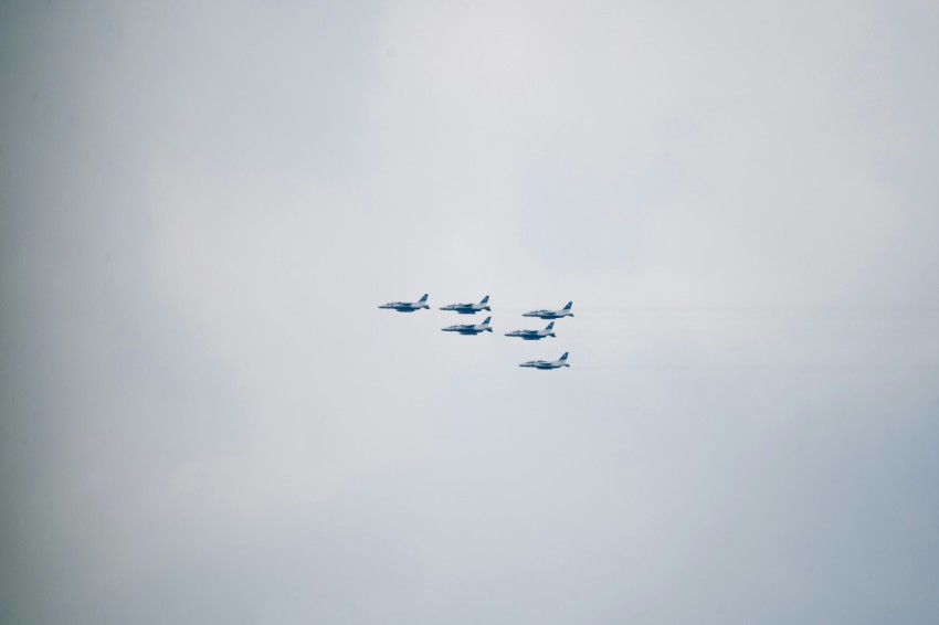 a group of fighter jets flying through a cloudy sky