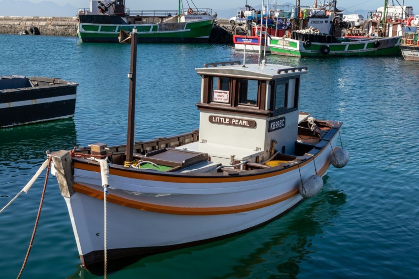 a small boat in the water with other boats in the background