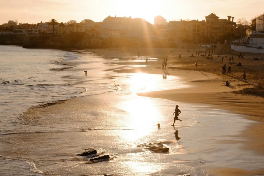 a group of people walking along a beach next to the ocean z4E