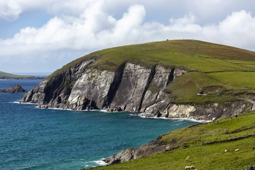 a large body of water sitting next to a lush green hillside