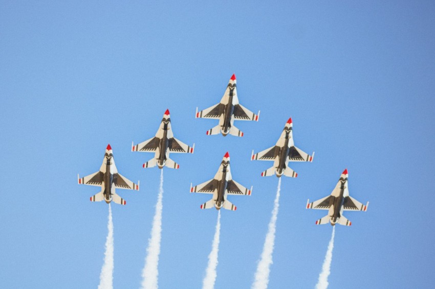 a group of fighter jets flying through a blue sky