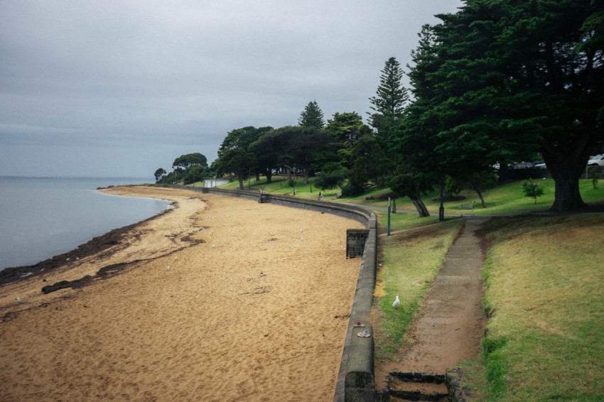 a sandy beach next to the ocean under a cloudy sky wB