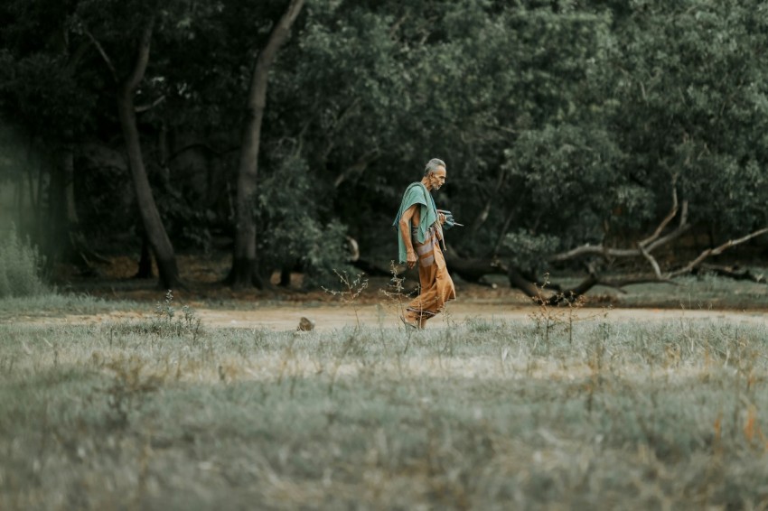 a man walking across a grass covered field