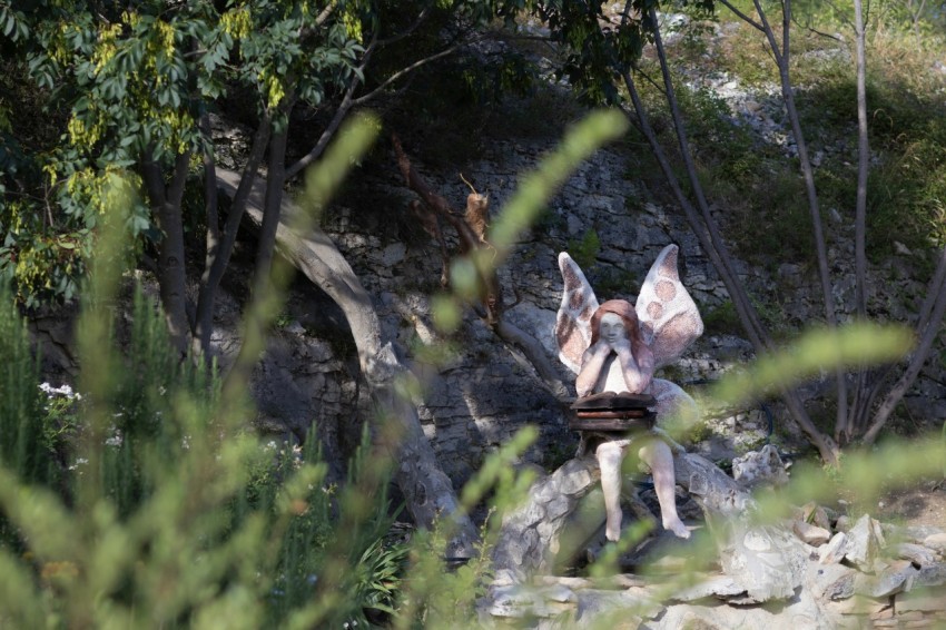 a woman with wings standing on a rock in the woods