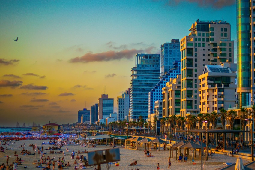 a crowded beach with tall buildings in the background zKyEk