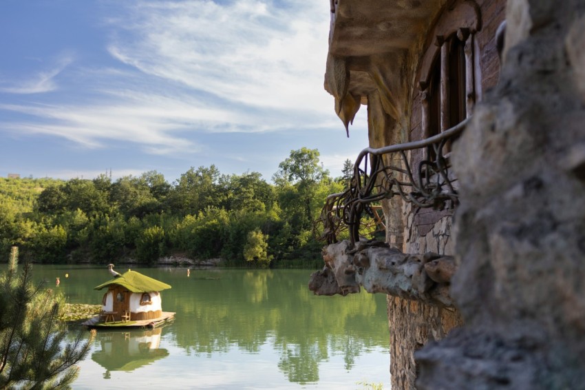 a boat floating on top of a lake next to a stone building