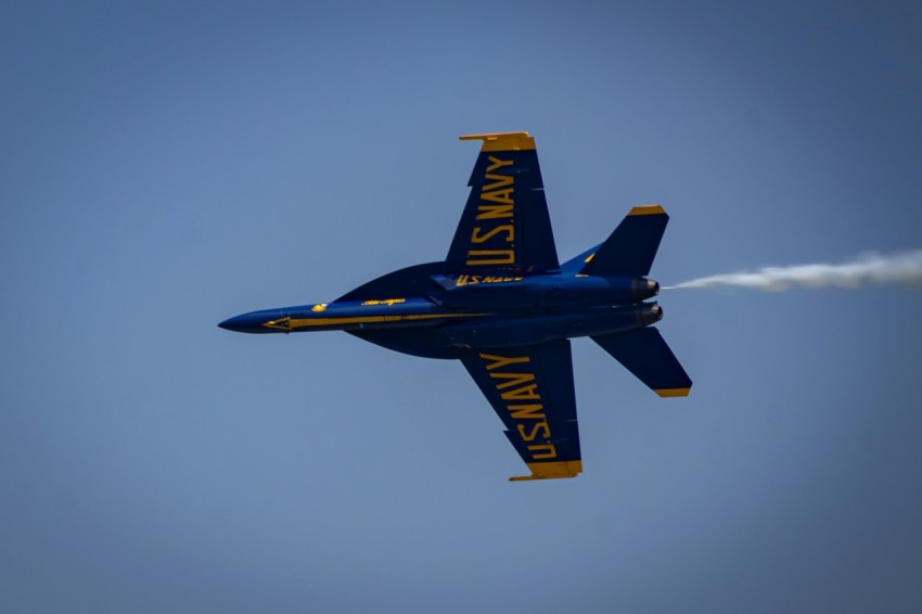 a blue and yellow jet flying through a blue sky