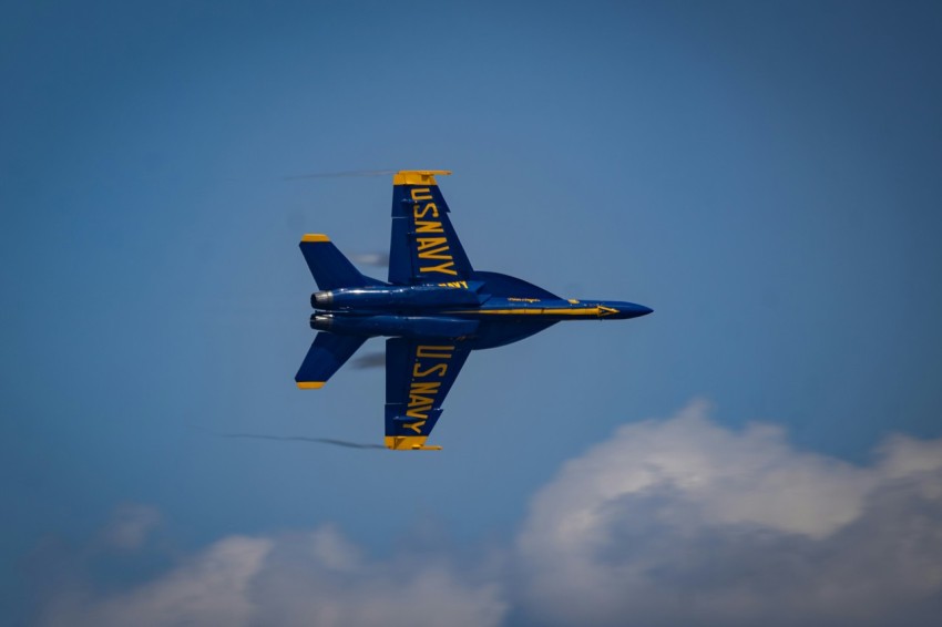 a blue and yellow plane flying in the sky