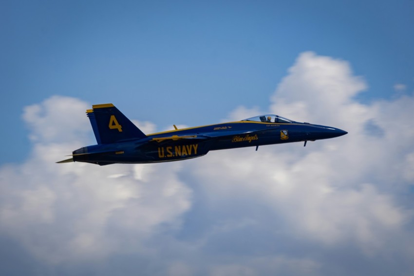 a fighter jet flying through a cloudy blue sky