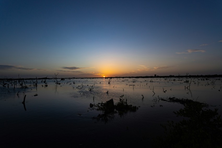 the sun is setting over a body of water XF6lCM