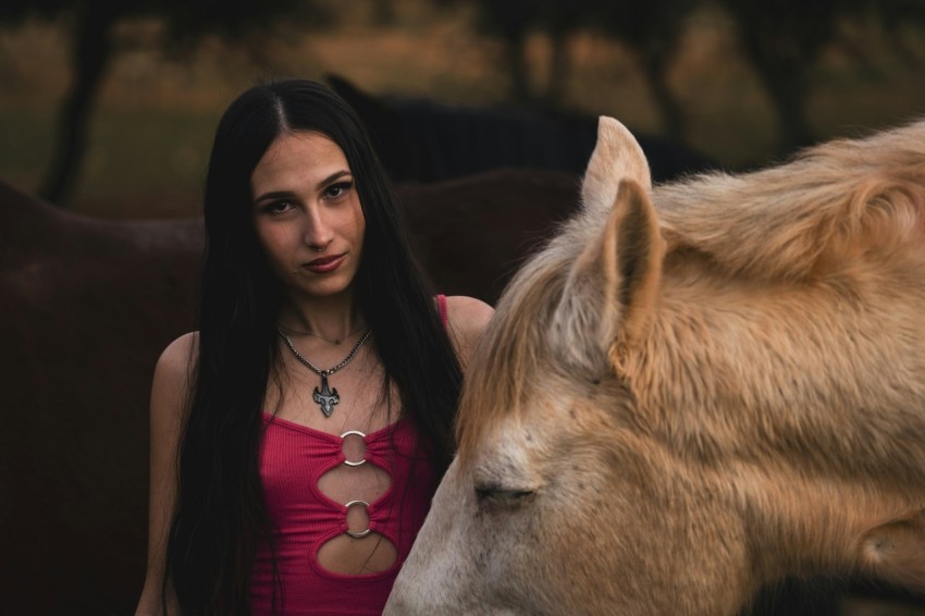 a woman standing next to a brown horse