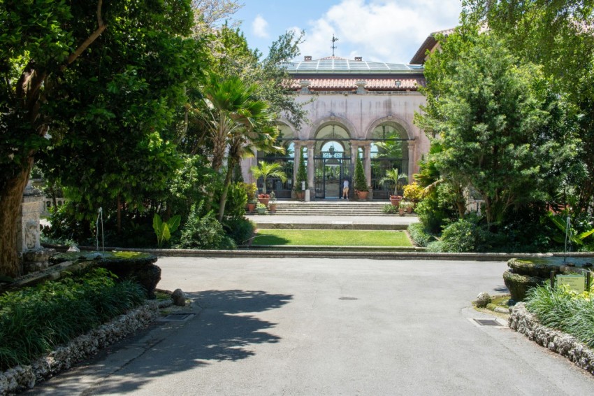 a driveway leading to a large building with a fountain in the middle of it