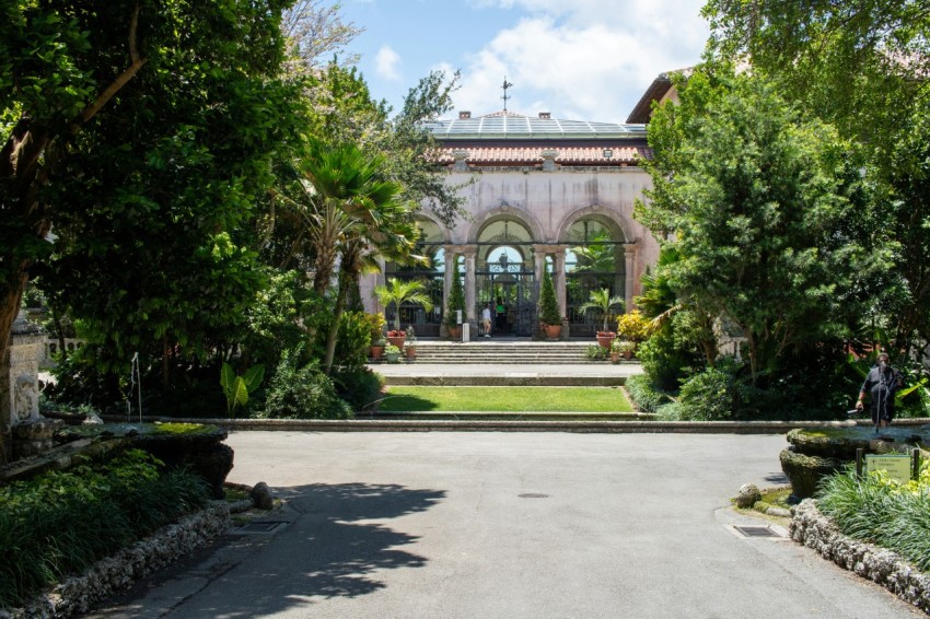 a driveway leading to a large building with a fountain in the middle of it