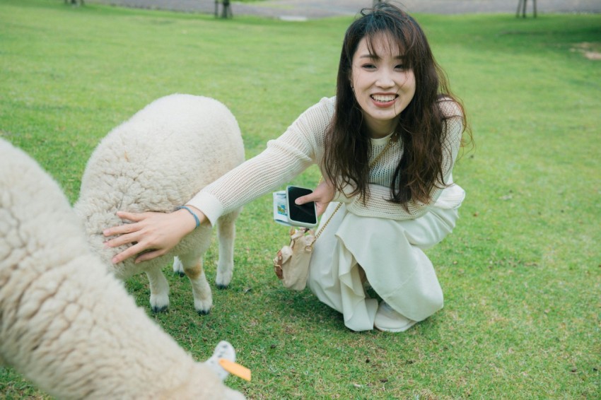 a woman kneeling down next to two sheep