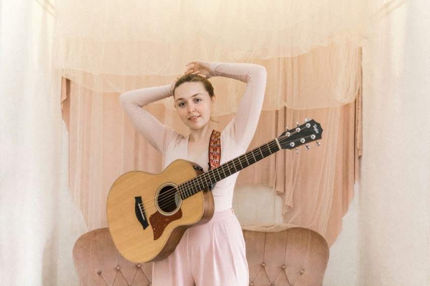 woman in pink sleeveless dress holding brown acoustic guitar rv