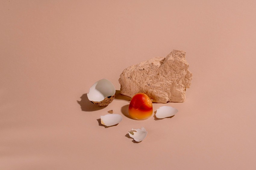 a piece of fruit sitting on top of a table next to eggs