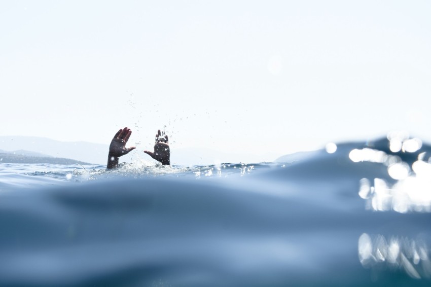 person swimming in water with hand raising