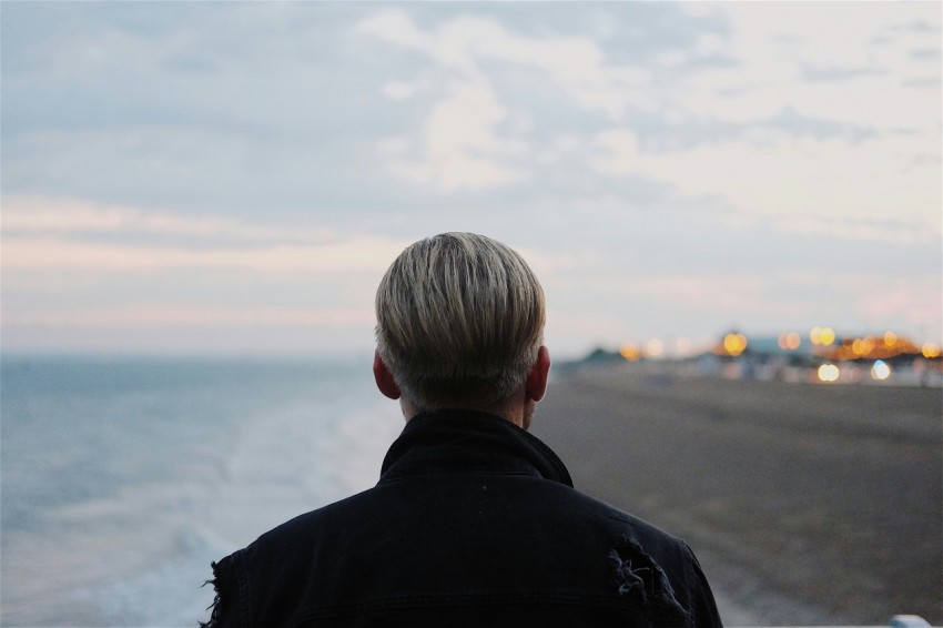 man in black coat walking on seashore