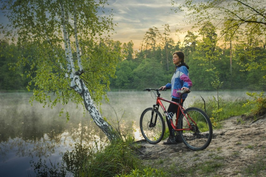 woman in blue shirt riding red and black mountain bike on river during daytime