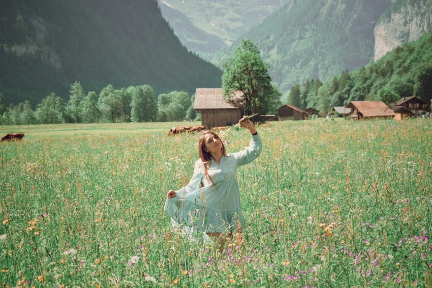 a woman standing in a field holding a bird above her head