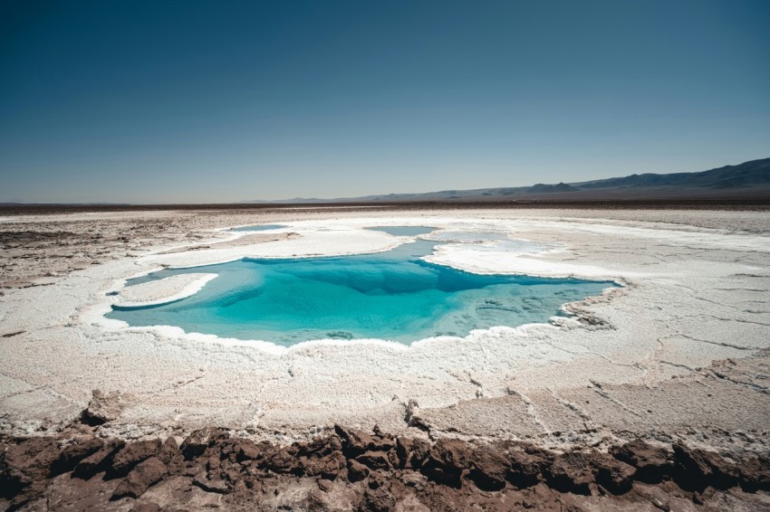 a blue pool of water in the middle of a desert