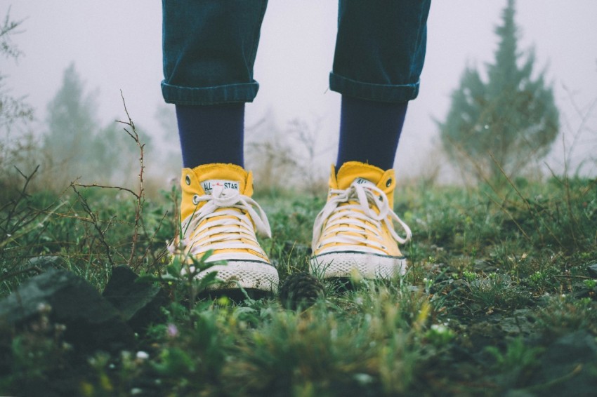 person in black pants and yellow sneakers standing on grass field AC0yU3Hda