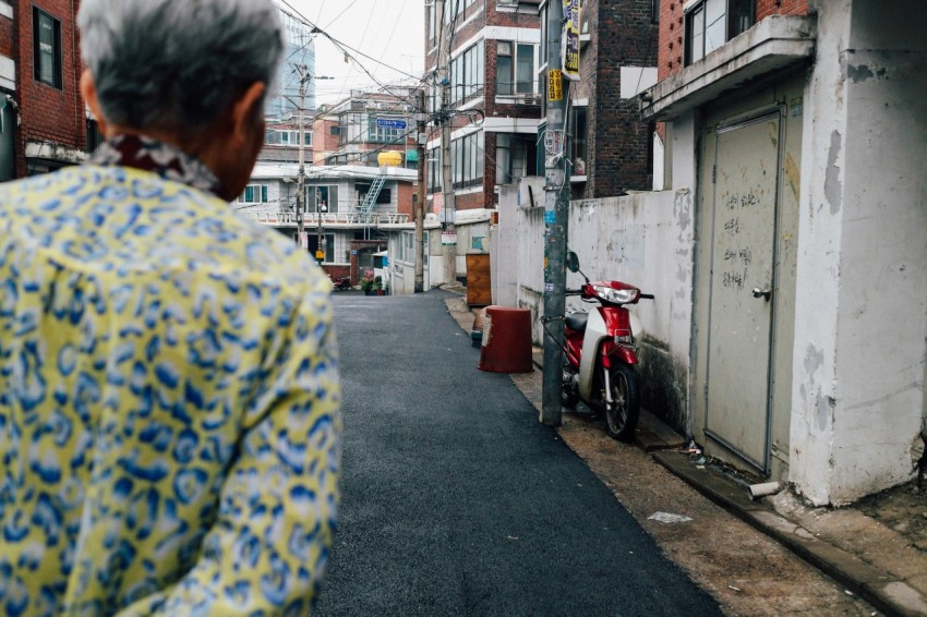 person walking on grey concrete road in front of red and white motorcycle during daytime