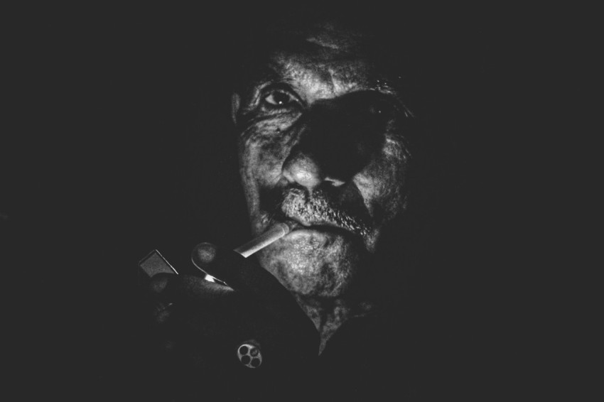 greyscale photo of man lighting cigarette close up photo