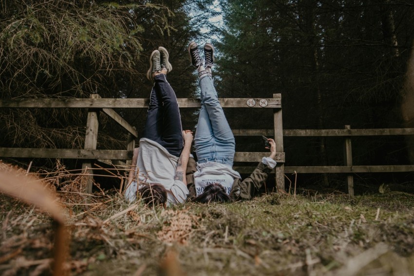 man and woman sitting on brown wooden fence during daytime