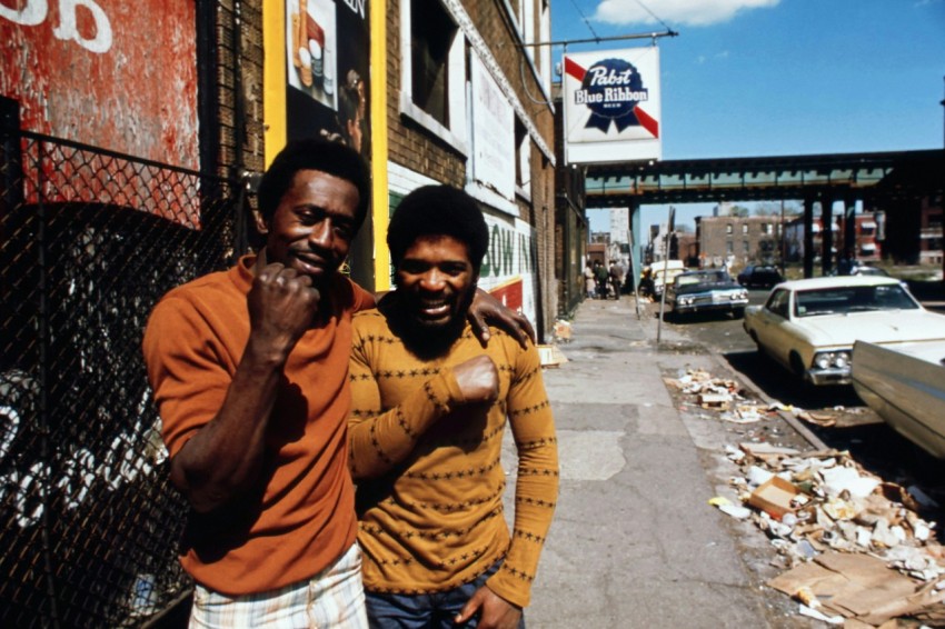 two men standing next to each other on a street