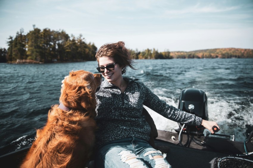 woman in black and white floral long sleeve shirt sitting beside brown long coated dog during