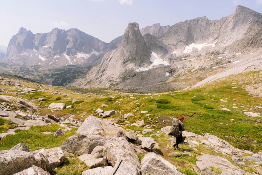 person in black jacket sitting on rock near gray rocky mountain during daytime